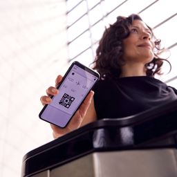 Reisende zeigt am Flughafen eine digitale Bordkarte auf dem Smartphone