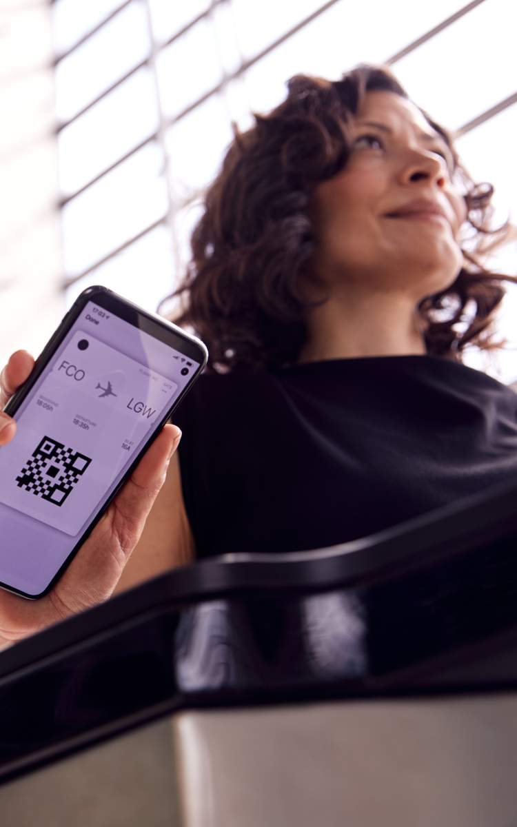 Reisende zeigt am Flughafen eine digitale Bordkarte auf dem Smartphone
