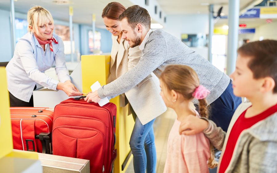 Familie bei der Gepäckabgabe am Check-in-Schalter